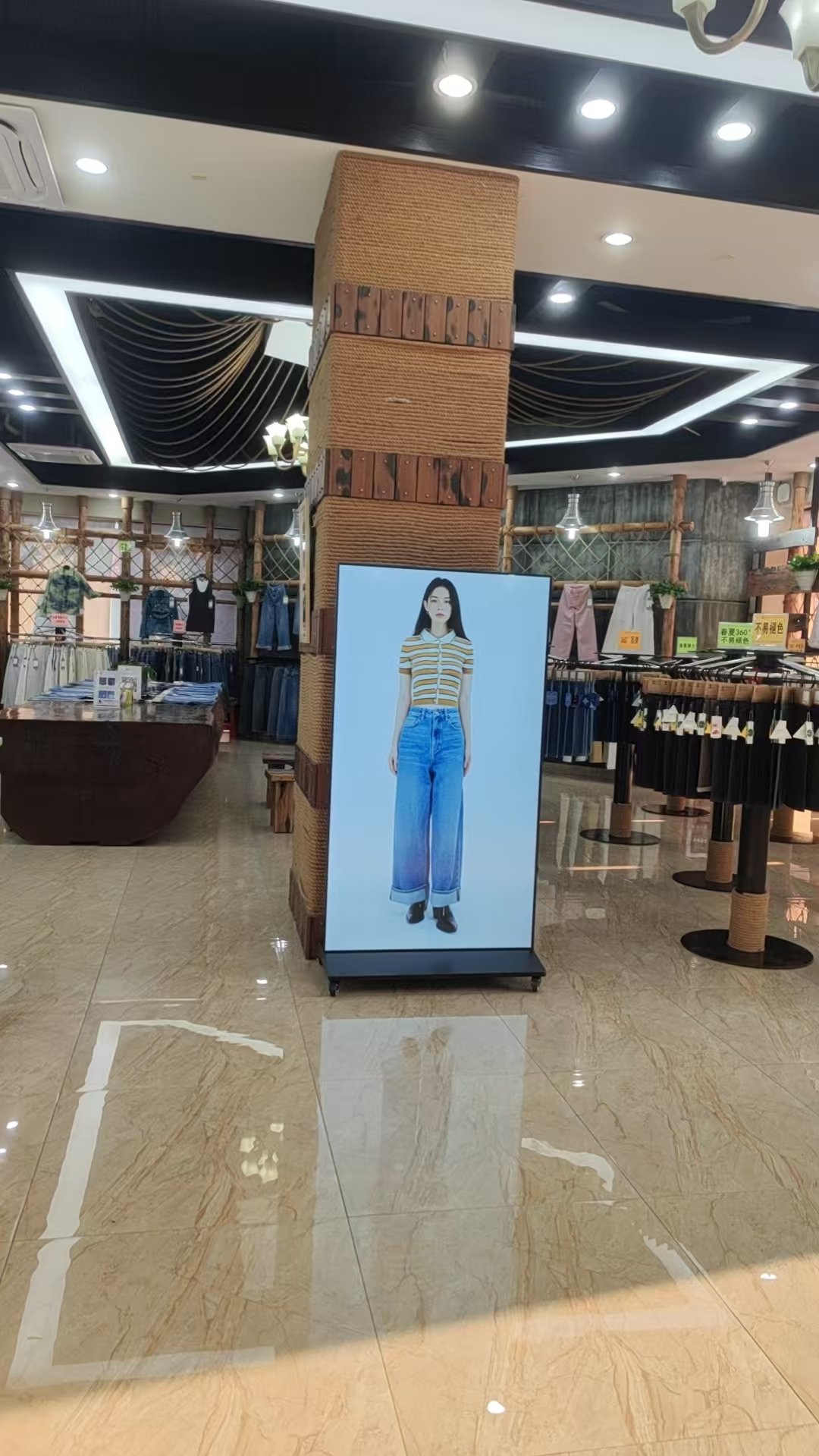 Single floor-standing LCD poster displaying fashion content inside a clothing retail store